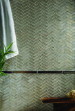 sandbar tile in a herringbone mosaic and Bronze bar liner shown as bathroom wall tile
