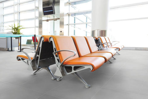 medium grey square tiles on commercial floor with orange modern furniture and large floor to ceiling windows in background