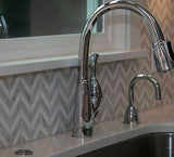 Silver kitchen sink against monochromatic marble tile accent wall in chevron mosaic