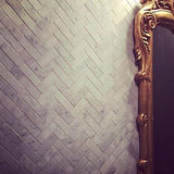Elegant gold mirror pops against dark Herringbone mosaic tile
