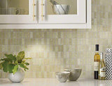 Trapezoid mosaic marble tile wall with white kitchen cabinets, potted plant, and stone bowls